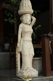 Photo of Bali, Indonesia - May 15, 2025: Beautiful ancient sculpture of woman with basket of fruits on city street