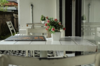 Photo of Cozy terrace of cafe with tables, chairs and decor, closeup