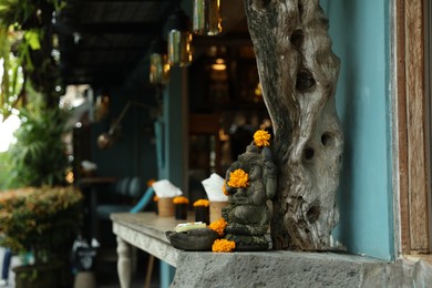 Photo of Bali, Indonesia - May 15, 2025: Beautiful Ganesha statue with ornament on cafe counter outdoors