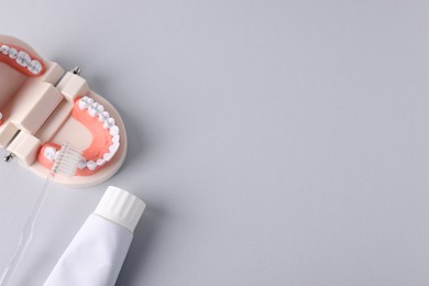 Photo of Dental model, toothpaste and toothbrush on light grey background, flat lay. Space for text