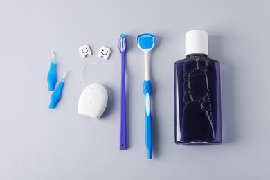 Photo of Different oral care products and teeth models on light grey background, flat lay