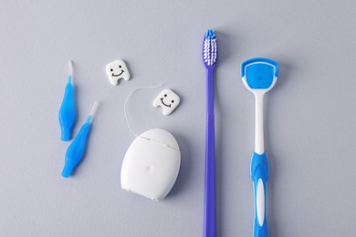 Photo of Different oral care products and teeth models on light grey background, flat lay