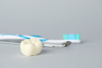 Photo of Different oral care products and tooth model on light grey background, closeup
