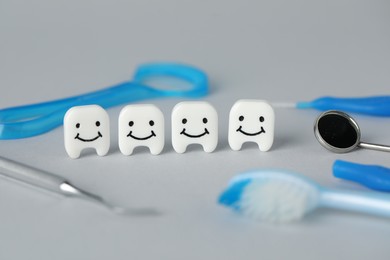 Photo of Different oral care products and teeth models on light grey background, closeup
