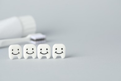 Photo of Different oral care products and teeth models on light grey background, closeup. Space for text