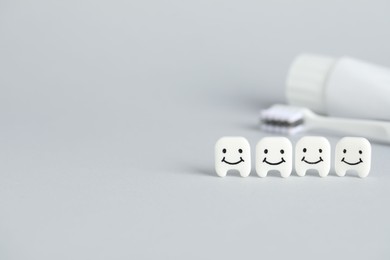 Photo of Different oral care products and teeth models on light grey background, closeup. Space for text