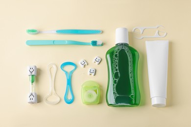 Photo of Different oral care products and teeth models on beige background, flat lay
