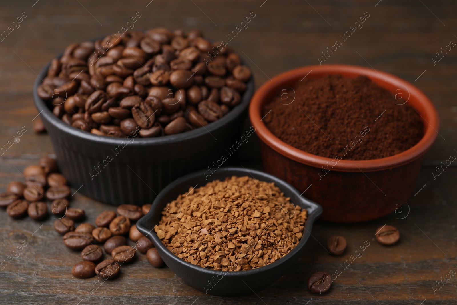 Different types of instant coffee and beans in bowls on wooden table, closeup Photo of Different types of instant coffee and beans in bowls on wooden table, closeup