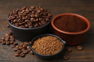 Photo of Different types of instant coffee and beans in bowls on wooden table, closeup