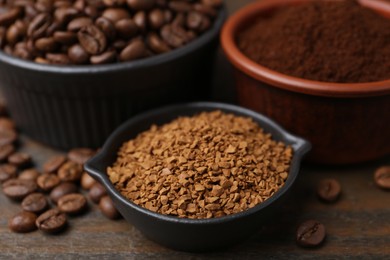 Photo of Different types of instant coffee and beans in bowls on wooden table, closeup