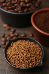 Photo of Different types of instant coffee and beans in bowls on wooden table, closeup