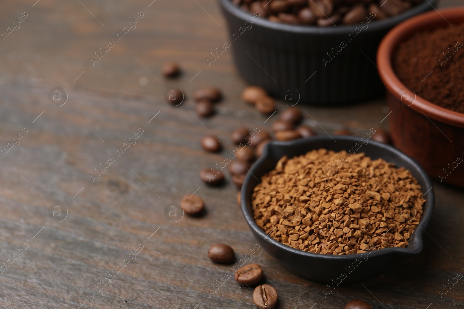 Different types of instant coffee and beans in bowls on wooden table, closeup. Space for text Photo of Different types of instant coffee and beans in bowls on wooden table, closeup. Space for text