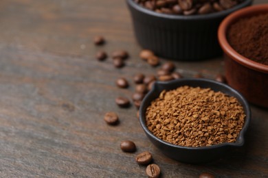 Photo of Different types of instant coffee and beans in bowls on wooden table, closeup. Space for text