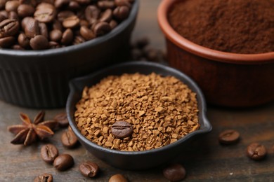 Photo of Different types of instant coffee and beans in bowls on wooden table, closeup