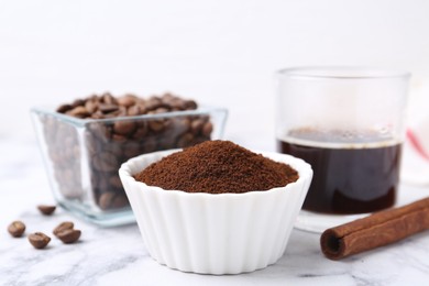Photo of Instant coffee powder in bowl, beans and drink on white marble table, closeup