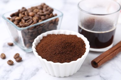 Photo of Instant coffee powder in bowl, beans and drink on white marble table, closeup