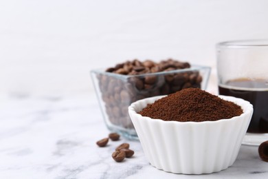 Photo of Instant coffee powder in bowl, beans and drink on white marble table, closeup. Space for text