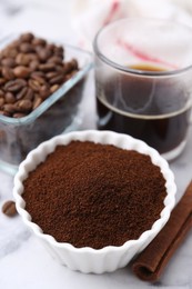 Photo of Instant coffee powder in bowl, beans and drink on white table, closeup