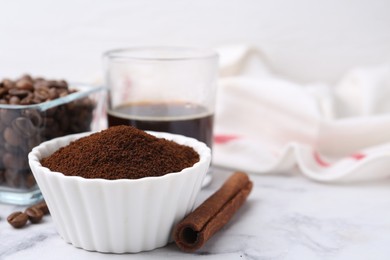 Photo of Instant coffee powder in bowl, cinnamon stick, beans and drink on white marble table, closeup. Space for text