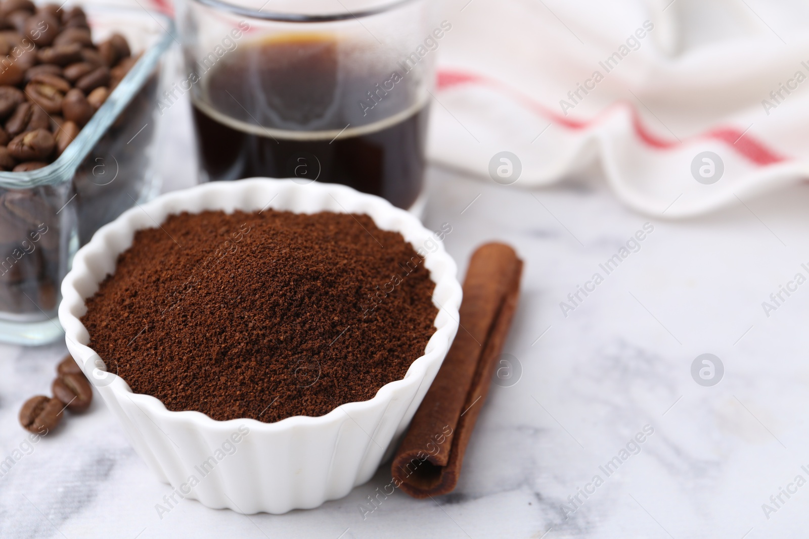 Instant coffee powder in bowl, cinnamon stick, beans and drink on white marble table, closeup. Space for text Photo of Instant coffee powder in bowl, cinnamon stick, beans and drink on white marble table, closeup. Space for text