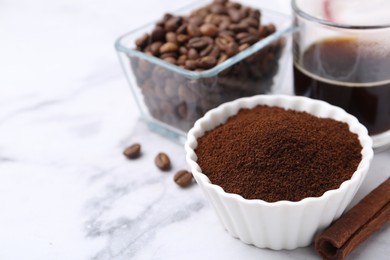 Photo of Instant coffee powder in bowl, cinnamon stick, beans and drink on white marble table, closeup. Space for text
