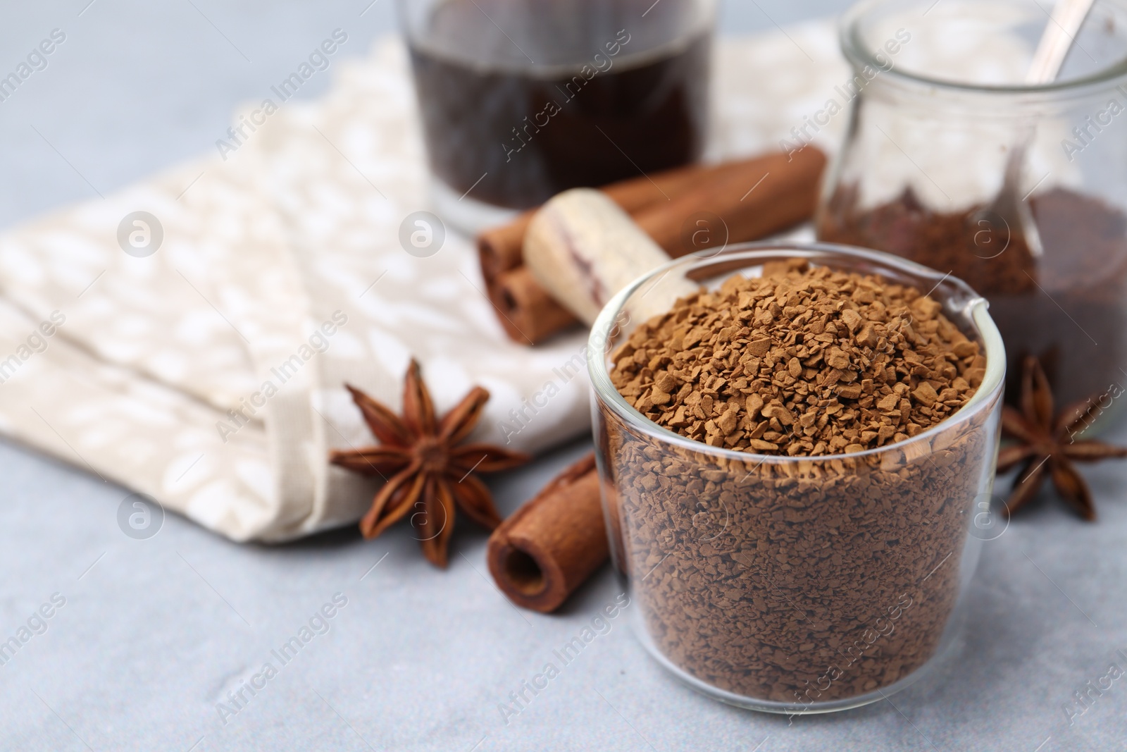 Granulated instant coffee in measuring cup and spices on grey table, closeup Photo of Granulated instant coffee in measuring cup and spices on grey table, closeup