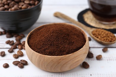 Photo of Instant coffee powder in bowl and beans on white wooden table, closeup