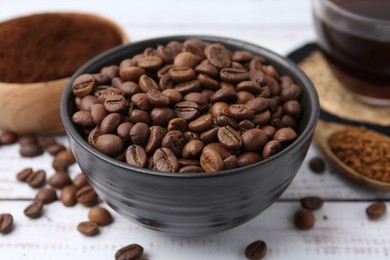 Photo of Roasted beans in bowl and different types of instant coffee on white wooden table, closeup
