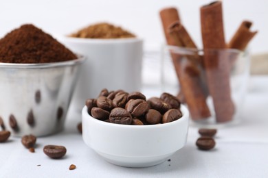 Photo of Roasted beans, different types of instant coffee and cinnamon sticks on light table, closeup