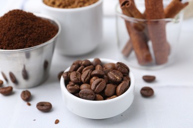 Photo of Roasted beans, different types of instant coffee and cinnamon sticks on light table, closeup
