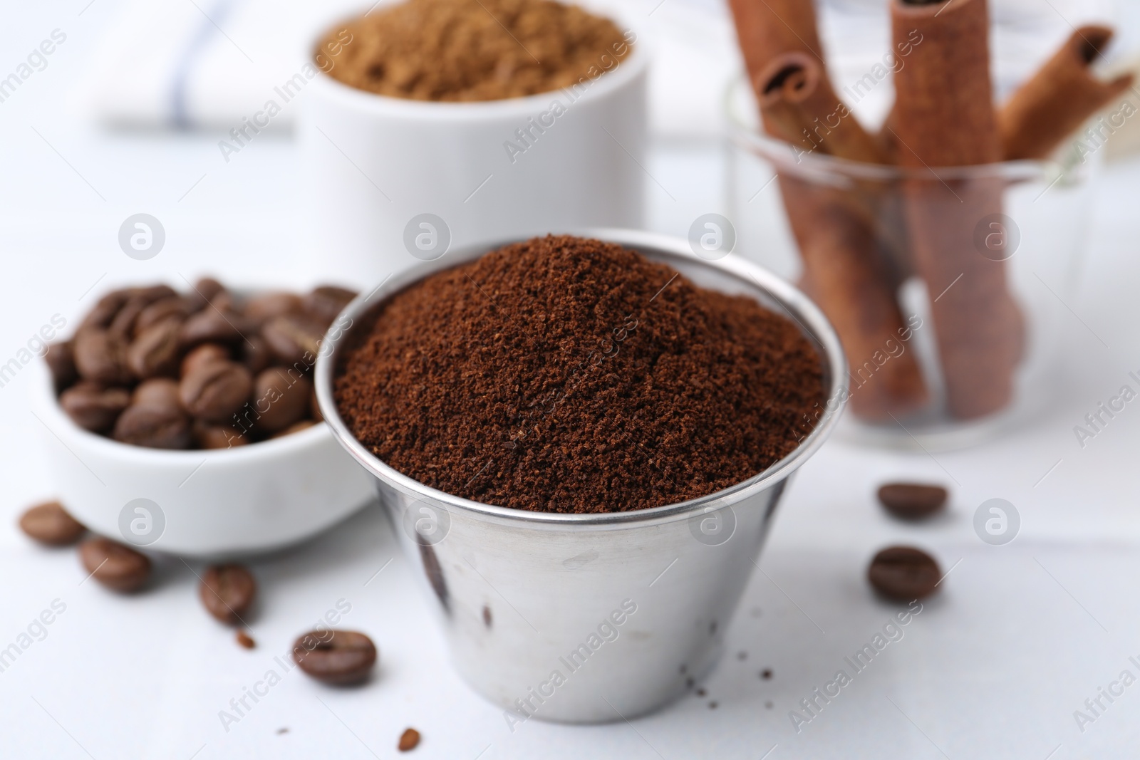 Instant coffee powder, beans and cinnamon sticks on light table, closeup Photo of Instant coffee powder, beans and cinnamon sticks on light table, closeup