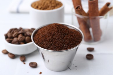Photo of Instant coffee powder, beans and cinnamon sticks on light table, closeup