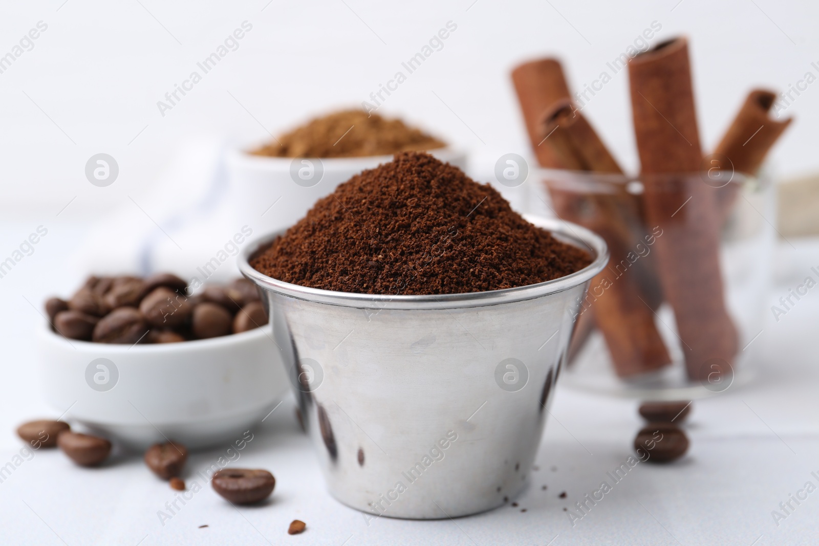 Instant coffee powder, beans and cinnamon sticks on light table, closeup Photo of Instant coffee powder, beans and cinnamon sticks on light table, closeup
