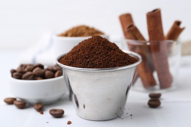 Photo of Instant coffee powder, beans and cinnamon sticks on light table, closeup