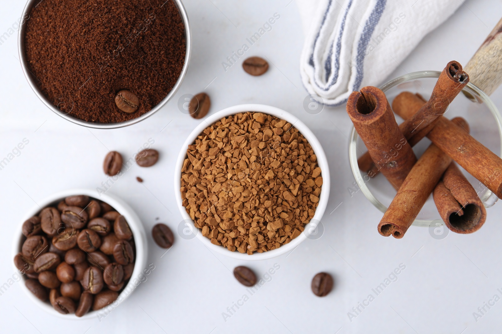 Different types of instant coffee, beans and cinnamon sticks on light table, flat lay Photo of Different types of instant coffee, beans and cinnamon sticks on light table, flat lay