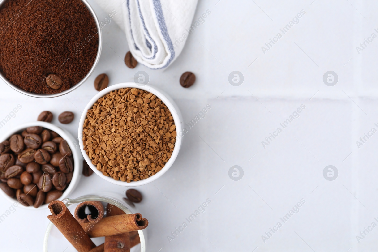 Different types of instant coffee, beans and cinnamon sticks on light tiled table, flat lay. Space for text Photo of Different types of instant coffee, beans and cinnamon sticks on light tiled table, flat lay. Space for text