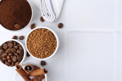 Photo of Different types of instant coffee, beans and cinnamon sticks on light tiled table, flat lay. Space for text