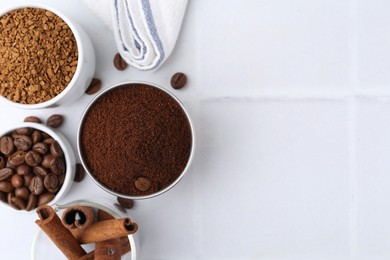 Photo of Different types of instant coffee, beans and cinnamon sticks on light tiled table, flat lay. Space for text