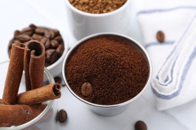 Photo of Instant coffee powder, beans and cinnamon sticks on light table, closeup