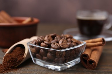 Photo of Roasted beans, instant coffee powder and cinnamon sticks on wooden table against brown background, closeup