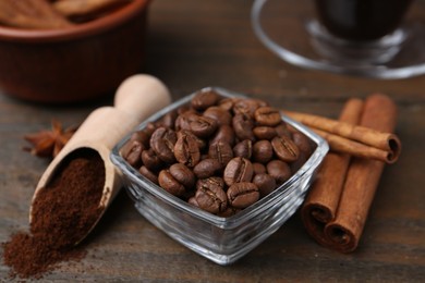 Photo of Roasted beans, instant coffee powder and cinnamon sticks on wooden table, closeup