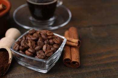 Photo of Roasted beans, instant coffee powder and cinnamon sticks on wooden table, closeup