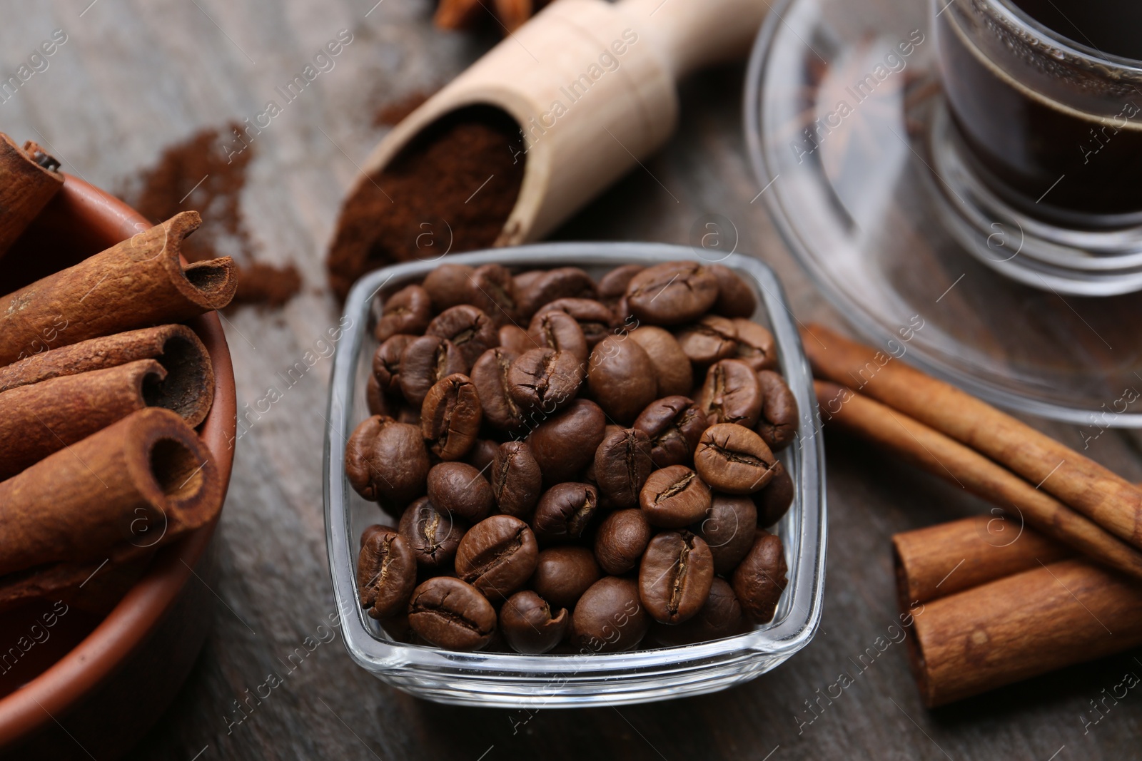 Roasted beans and cinnamon sticks on wooden table, closeup Photo of Roasted beans and cinnamon sticks on wooden table, closeup