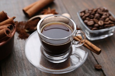 Photo of Refreshing coffee in cup and cinnamon stick on wooden table, closeup