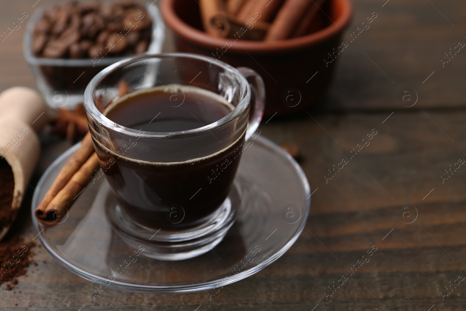 Refreshing coffee in cup and cinnamon stick on wooden table, closeup Photo of Refreshing coffee in cup and cinnamon stick on wooden table, closeup