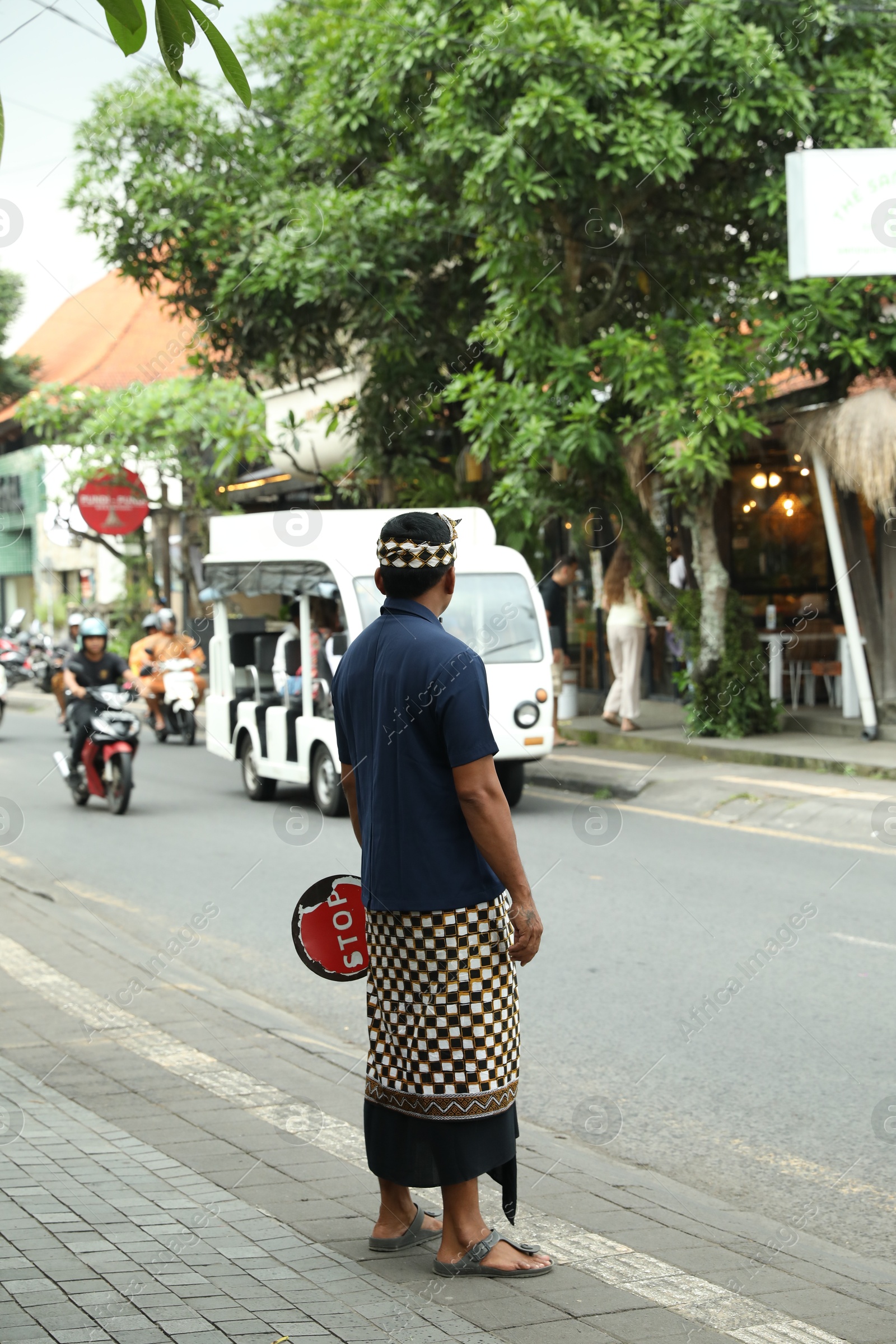 Bali, Indonesia - May 22, 2025: Traffic controller with stop sign near road in city Photo of Bali, Indonesia - May 22, 2025: Traffic controller with stop sign near road in city