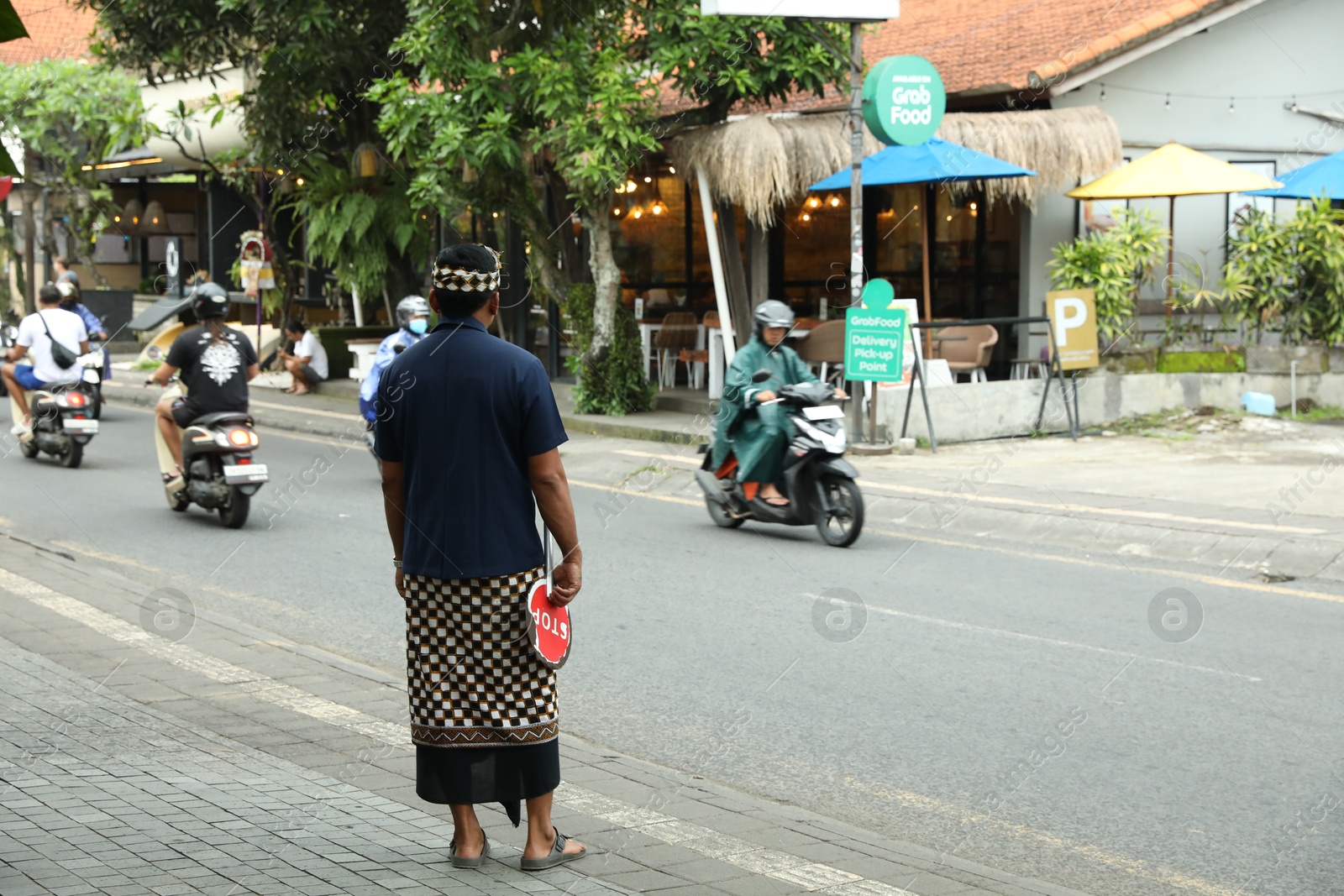 Bali, Indonesia - May 22, 2025: Traffic controller with stop sign near road in city Photo of Bali, Indonesia - May 22, 2025: Traffic controller with stop sign near road in city