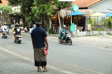 Photo of Bali, Indonesia - May 22, 2025: Traffic controller with stop sign near road in city