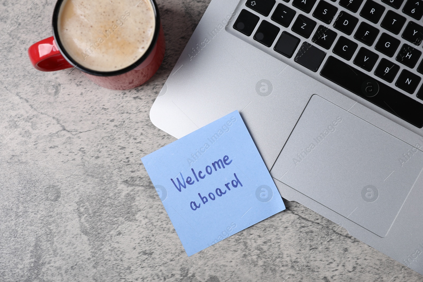 Sticky note with phrase Welcome Aboard, laptop and coffee on grey table, flat lay Photo of Sticky note with phrase Welcome Aboard, laptop and coffee on grey table, flat lay