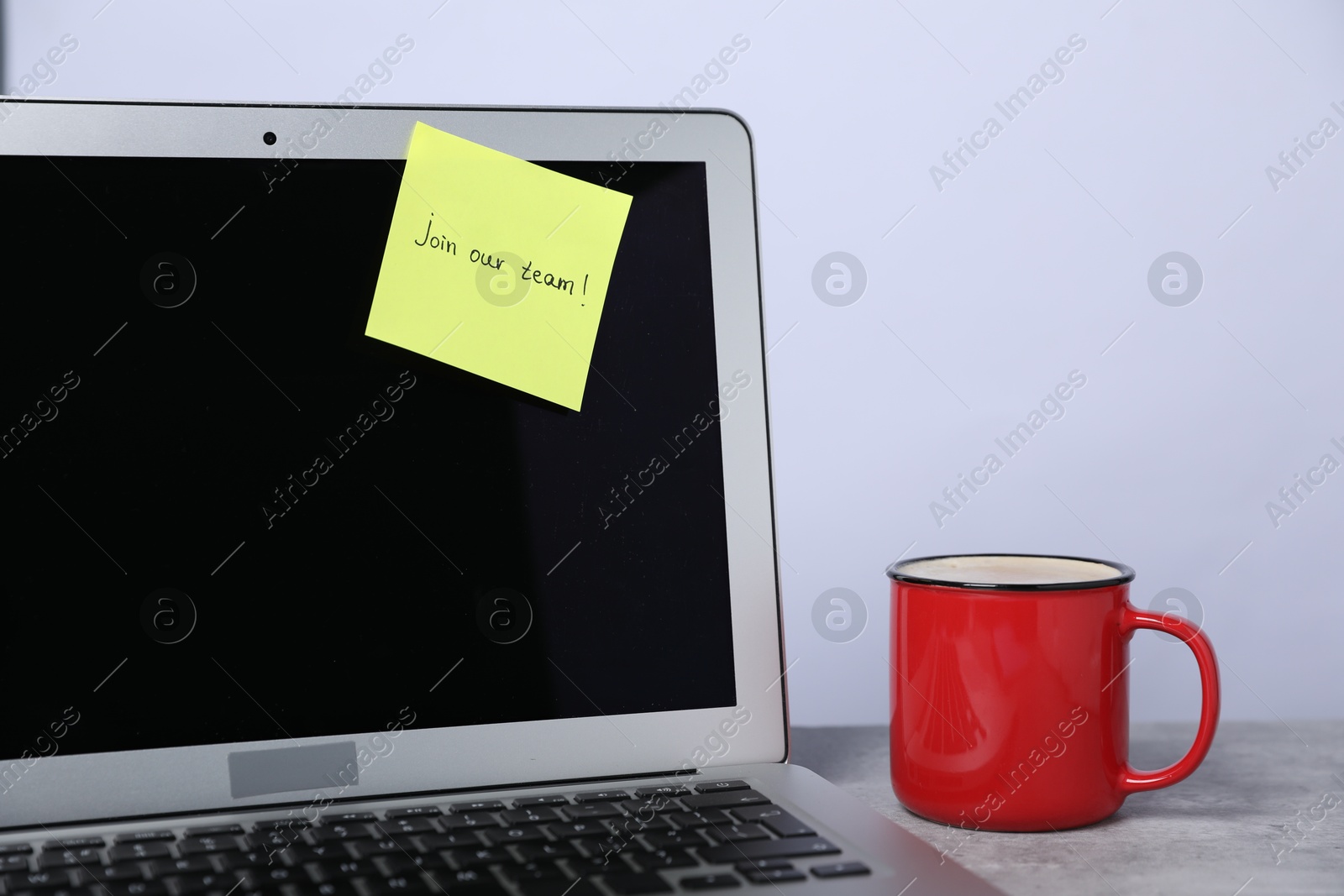 Sticky note with phrase Join Our Team, laptop and coffee on grey table, closeup Photo of Sticky note with phrase Join Our Team, laptop and coffee on grey table, closeup